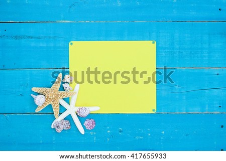 Blank yellow sign with starfish and seashells border on antique rustic teal blue wood background