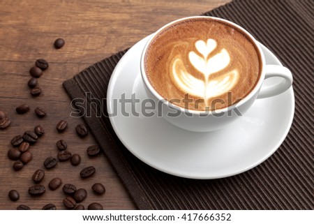 Coffee latte art tulip style in a cup on dark wooden table