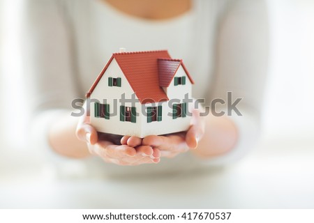 architecture, building, construction, real estate and property concept - close up of hands holding house or home model Royalty-Free Stock Photo #417670537