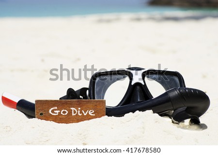 "Go Dive" text on wooden keychain withs scuba diving mask and snorkel on the tropical white sand beach - vacation and business concept