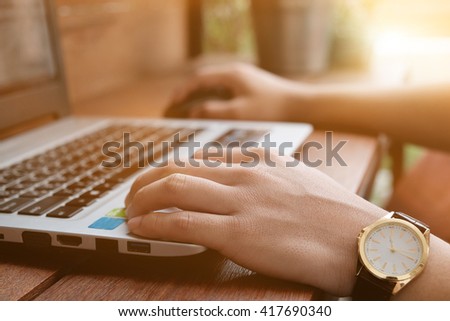 Close up of business man hand working on laptop on office desk in morning light.Vintage effect
