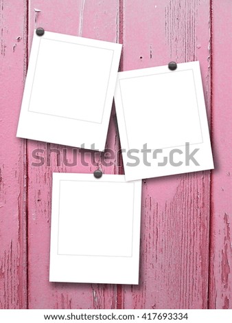 Close-up of three blank instant photo frames with pins on pink wooden background