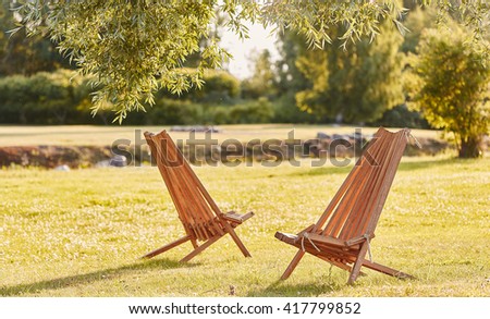 Two wooden chaise lounge in a park.