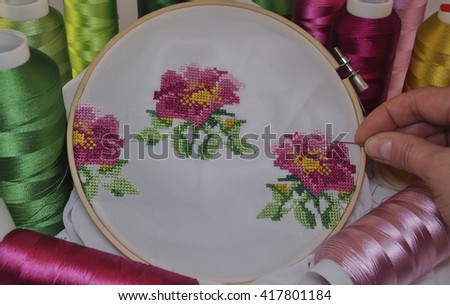 Hand embroidery cross wooden hoop on the background of multi-colored threads