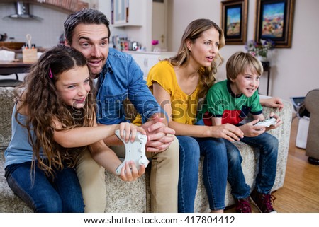 Family sitting on sofa and playing video game at home