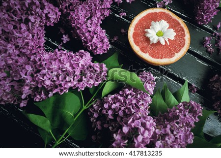 Flat lay. Halves grapefruit located on a dark surface among the lilac flowers. Photography can be used for nutrition articles, diet, recipes, fitness. sport, background, card.