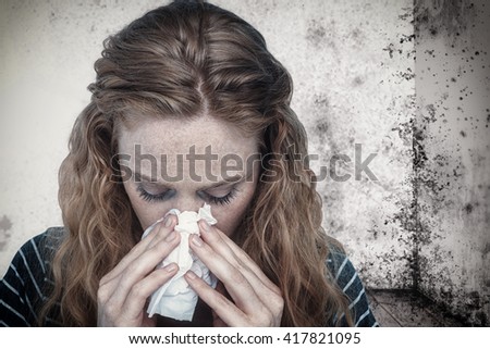 Close-up of woman blowing nose into tissue against image of a room corner