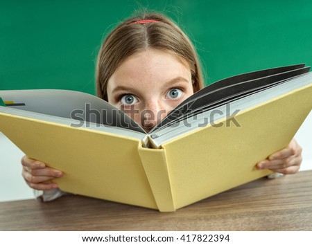 Surprised teenage girl with book. Photo of teen school girl, creative concept Back to school