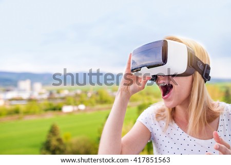 Woman wearing virtual reality goggles standing in a kitchen