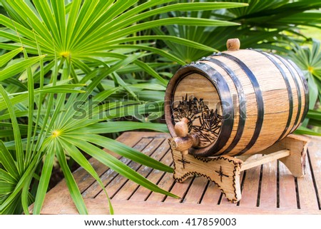 Small barrel for alcoholic drinks. Wooden barrel. Mini barrel.Barrel of tequila on background of palm branches