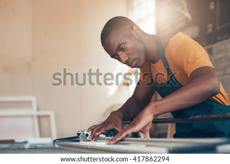 Skilled young African craftsman working in picture framing workshop Royalty-Free Stock Photo #417862294
