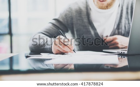 Working process photo. Manager working table with new startup project. Modern notebook table. Using pen for sign contract. Horizontal. Film effect. Blurred background