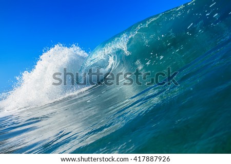 Shorebreak surfing tube wave. Pipeline in daylight with light of sun. Green Blue Ocean Water. Surfing template design with nobody. White splashes and ocean foam. Sky with no clouds. Surfing Rip Curl.