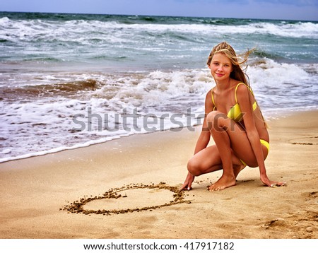 Summer girl sea.  Girl in swimsuit write on sand  heart shape . Summer vacation on sea.