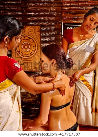 Woman having Ayurvedic spa massage treatment. Pouring oil massage.
