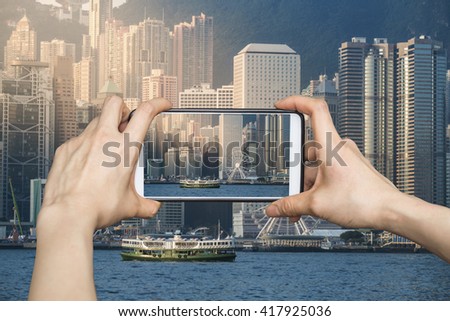 Girl taking pictures on mobile smart phone in Hong Kong's Victoria Harbour in sunrise