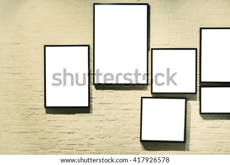 A bunch of empty black picture frames on white brick wall.
