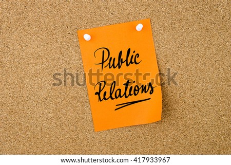 Public Relations written on orange paper note pinned on cork board with white thumbtacks, copy space available