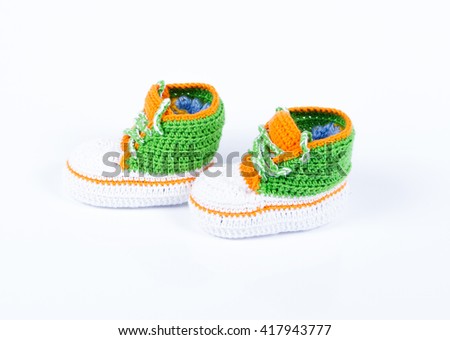 Little baby shoes. Hand knitted sneakers for newborn boy or girl. Crochet handmade bootees on white background.
