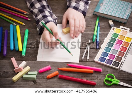 hand with stationary on wooden background