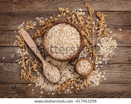 oats in a spoon in a plate on a table scattered oat flakes. Royalty-Free Stock Photo #417963298