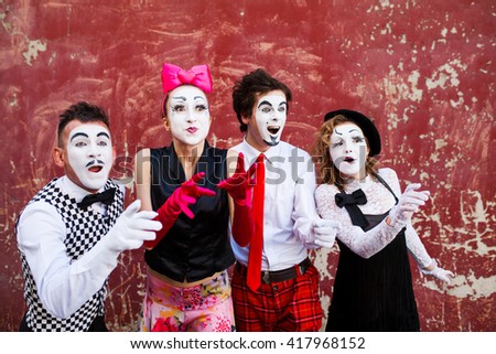 Four mimes looking aside on the background of a red wall. Royalty-Free Stock Photo #417968152