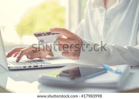 Woman's hands holding a credit card and using laptop for online shopping