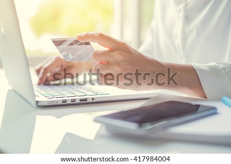 Woman's hands holding a credit card and using laptop for online shopping