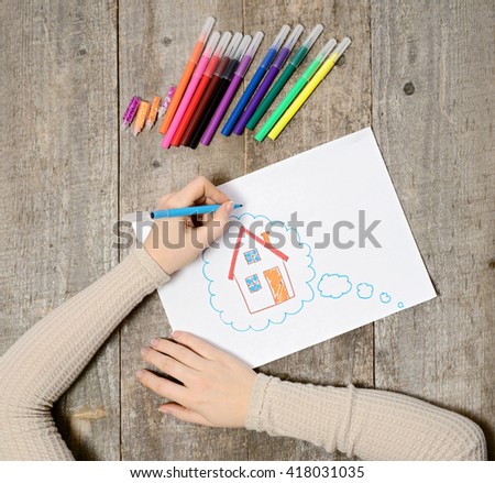A woman hand with pencil is drawing picture of country house