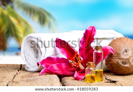 spa massage setting with lilium, oil, towel and salt on wood with tropical beach background