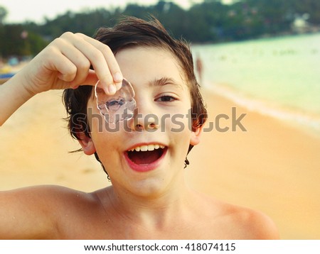 preteen handsome boy look through jellyfish on the seaside beach background close up photo