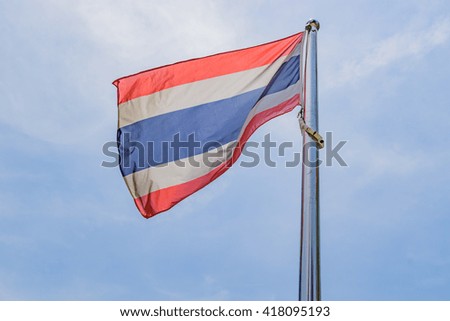 Waving Thai flag of Thailand with blue sky background.