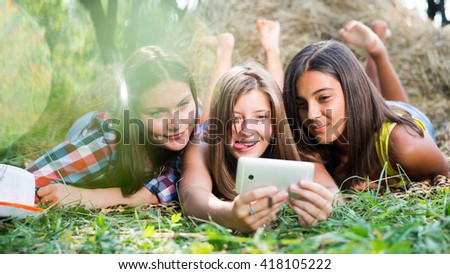 Picture of three happy girlfriends doing selfie by phone or tablet on summer outdoors background
