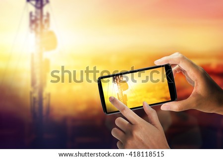 Hand with a smartphone take photo a antenna. Sunset background. communicate concept