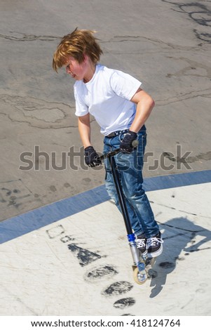 young boy has fun jumping with the push scooter at the skate park