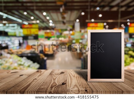 Blank price list board on wooden top table with blurred of supermarket background