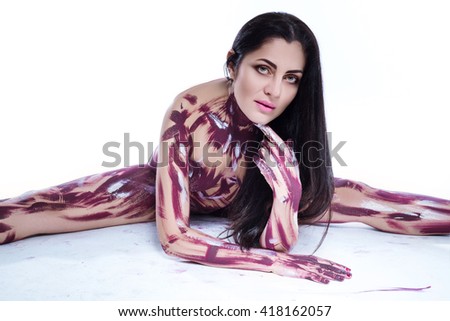 beautiful brunette with long hair sitting on white background, bodi coated with paint as art.