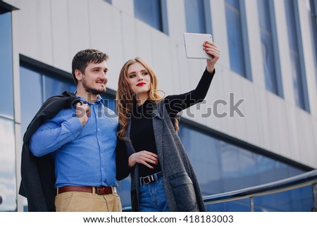 Brutal guy and a cute girl doing a selfie near business center.