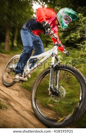 Close up of young woman downhill mountain biking in forest