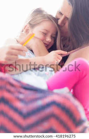 Daughter sitting on mother's lap, laughing