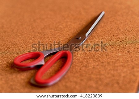 Red scissors on the cork table