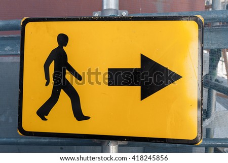 Pedestrians bypass direction. Yellow road sign on construction site border