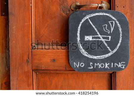 no smoking sign on blackboard and wooden door