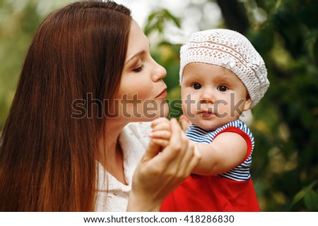 Portrait of Loving Young Mother Holding and Kissing Her Baby. Close Up Composition. 