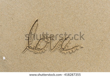 Love written on sand at sunrise time . selective focus.Conceptual abstract font in sand on exotic beach sea shore handwritten in sandy texture background in summer.