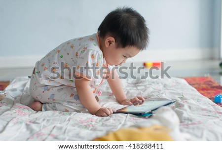 little asian boy playing digital tablet, early learning