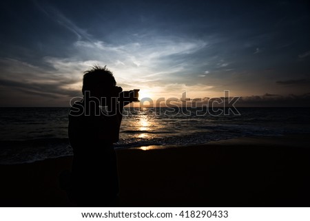 Silhouette of photographer taking photo on the beach before sunset time