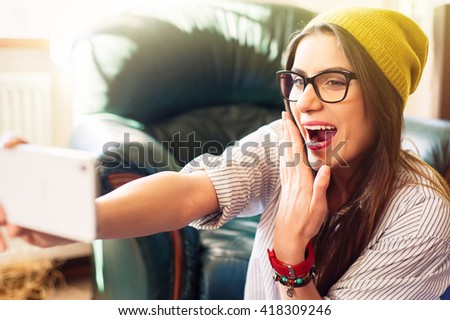 Pretty hipster girl taking selfie holding hand in front of mouth.