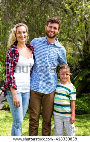 Portrait of happy family standing against trees at yard