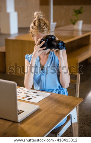 Woman clicking photo from camera in office